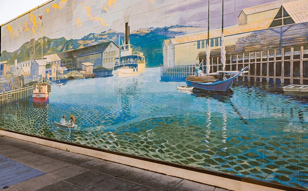 A mural of a harbor scene with boats and buildings